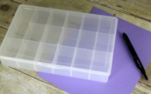 plastic organizer box with a sheet of purple cardstock and a black sharpie marker
