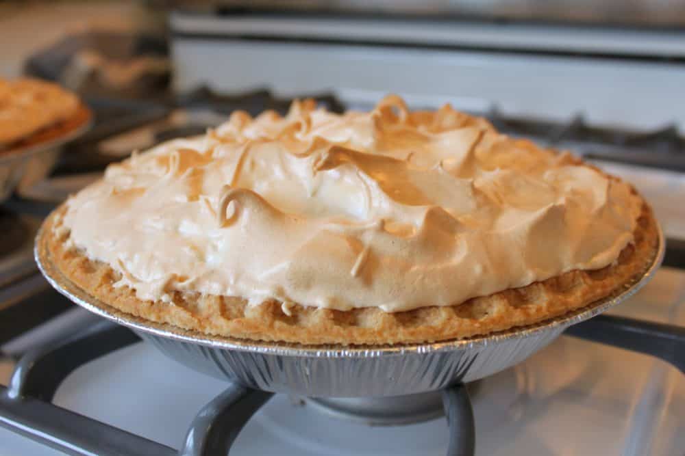 a lemon meringue pie cooling after baking in the oven