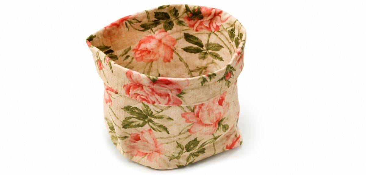 Floral fabric teacup with the top edge folded and stitched into a finished hem, ready for adding a handle and decorative details.