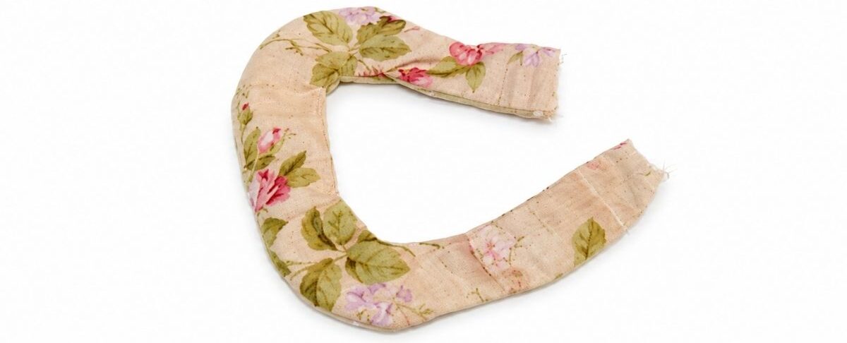 Floral fabric teapot handle sewn and turned right side out, shown curved and ready to be stuffed and attached to a fabric teapot.