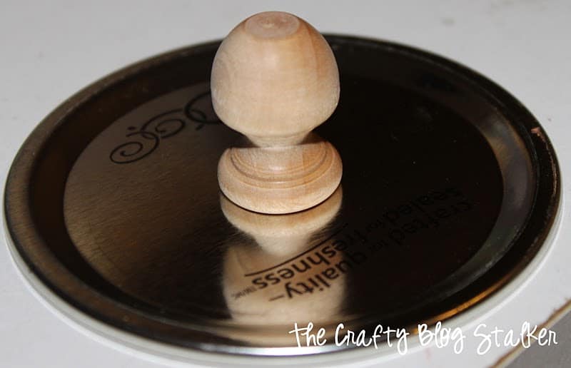 Flat canning jar lid with wood knob glued to the center.