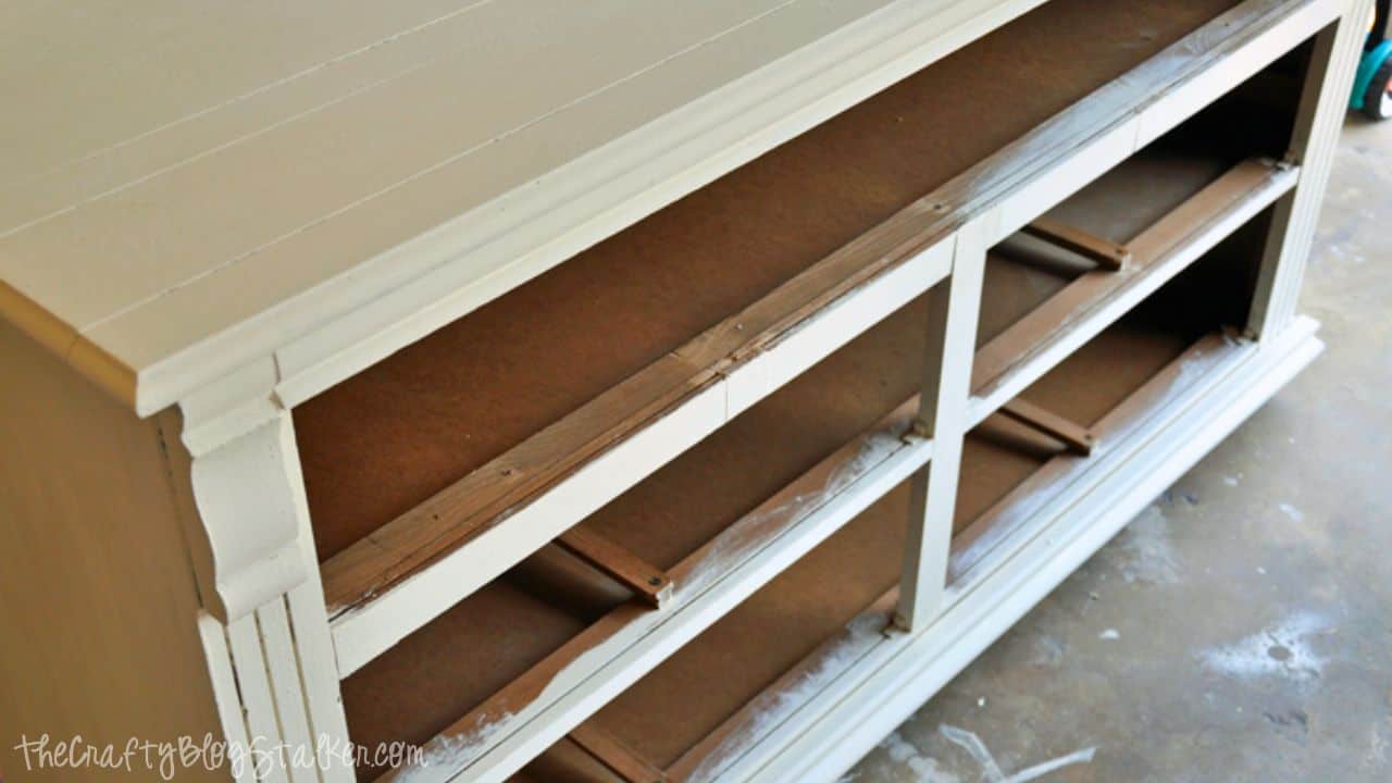 Top-down view of a dresser frame painted in light chalk paint, showing removed drawers and visible wooden drawer supports inside.