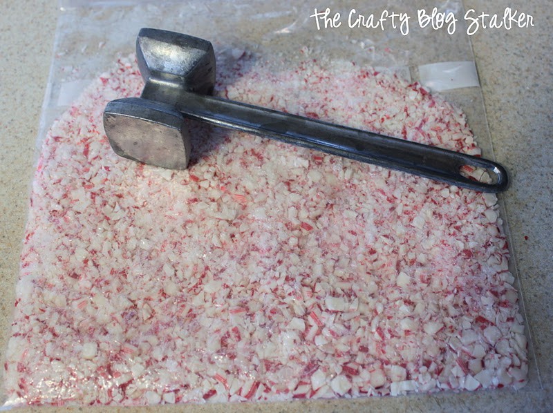 A zipper bag filled with crushed candy canes, and a kitchen mallet on top.