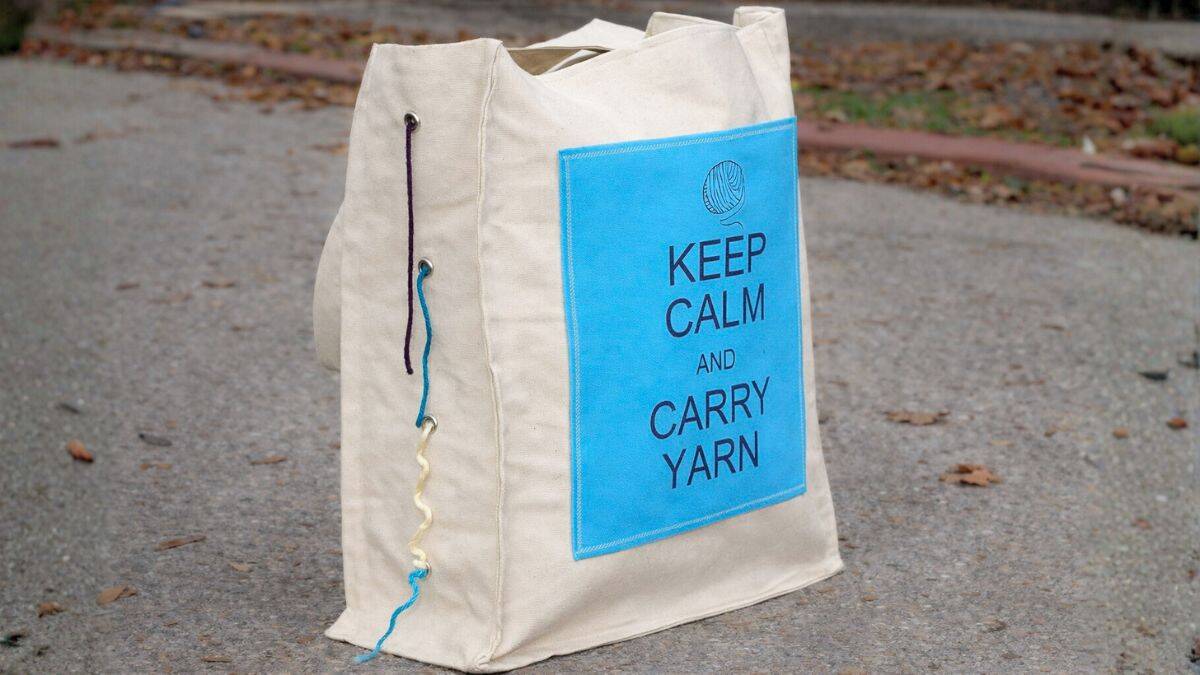 Finished canvas yarn tote bag with blue Keep Calm and Carry Yarn panel and grommets for feeding yarn while crocheting.