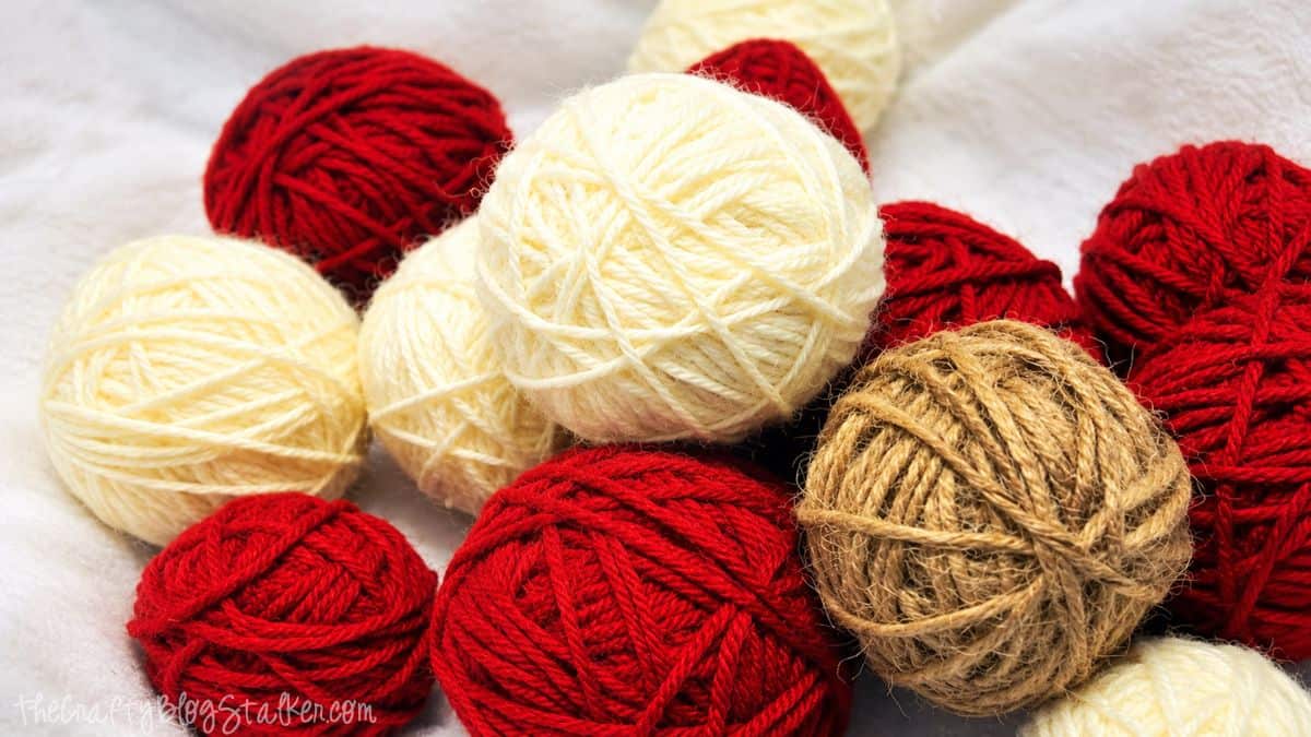 Red, cream, and tan yarn-wrapped balls in assorted sizes for making a DIY yarn ball wreath.