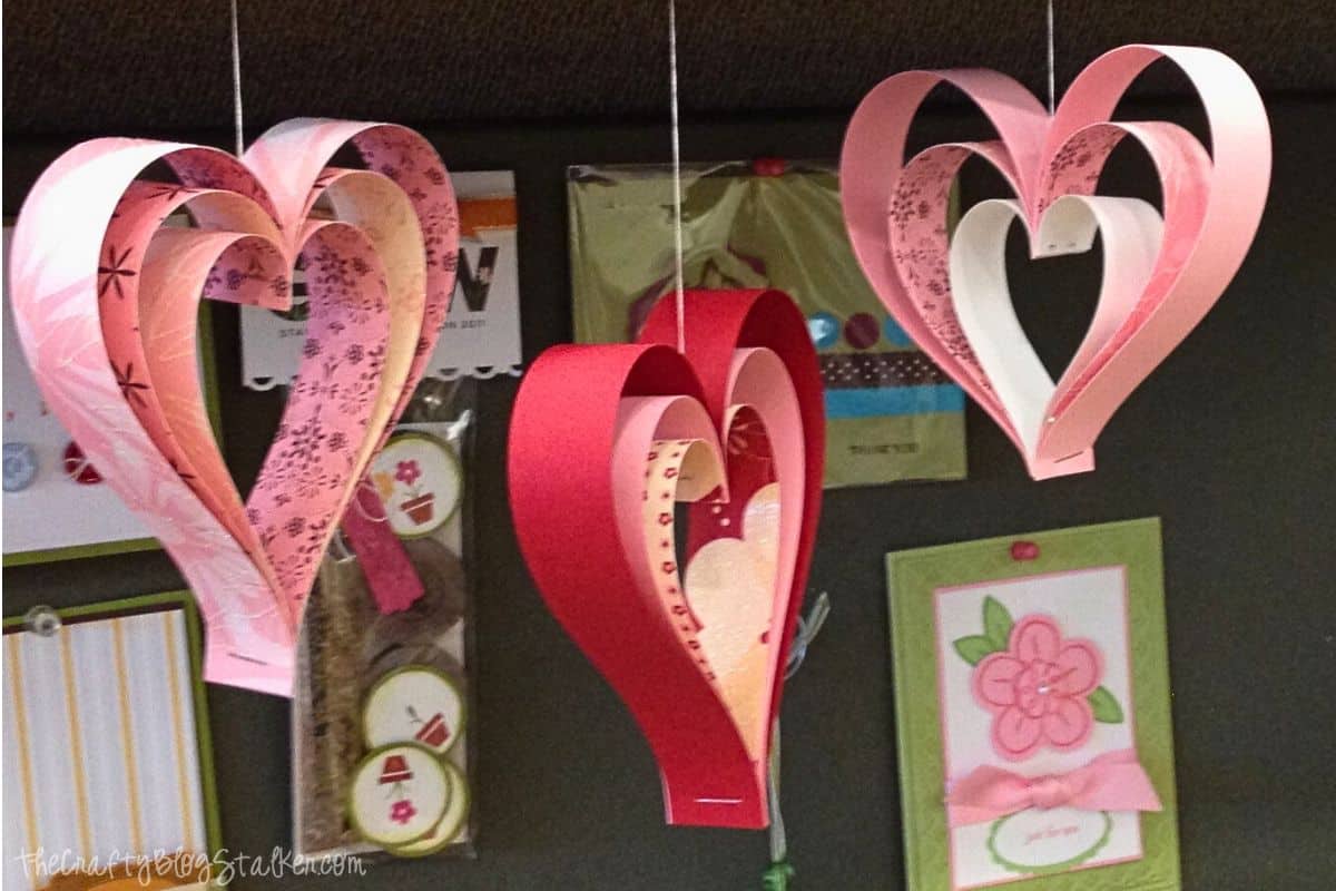 Three paper strip hearts hanging from a shelf.