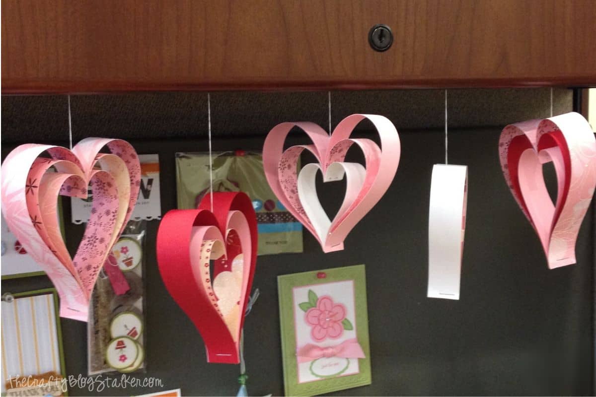 Five paper strip hearts hanging from a shelf.