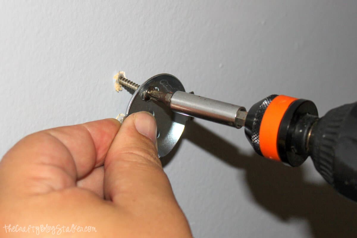 using a drill to screw the holder into the wall