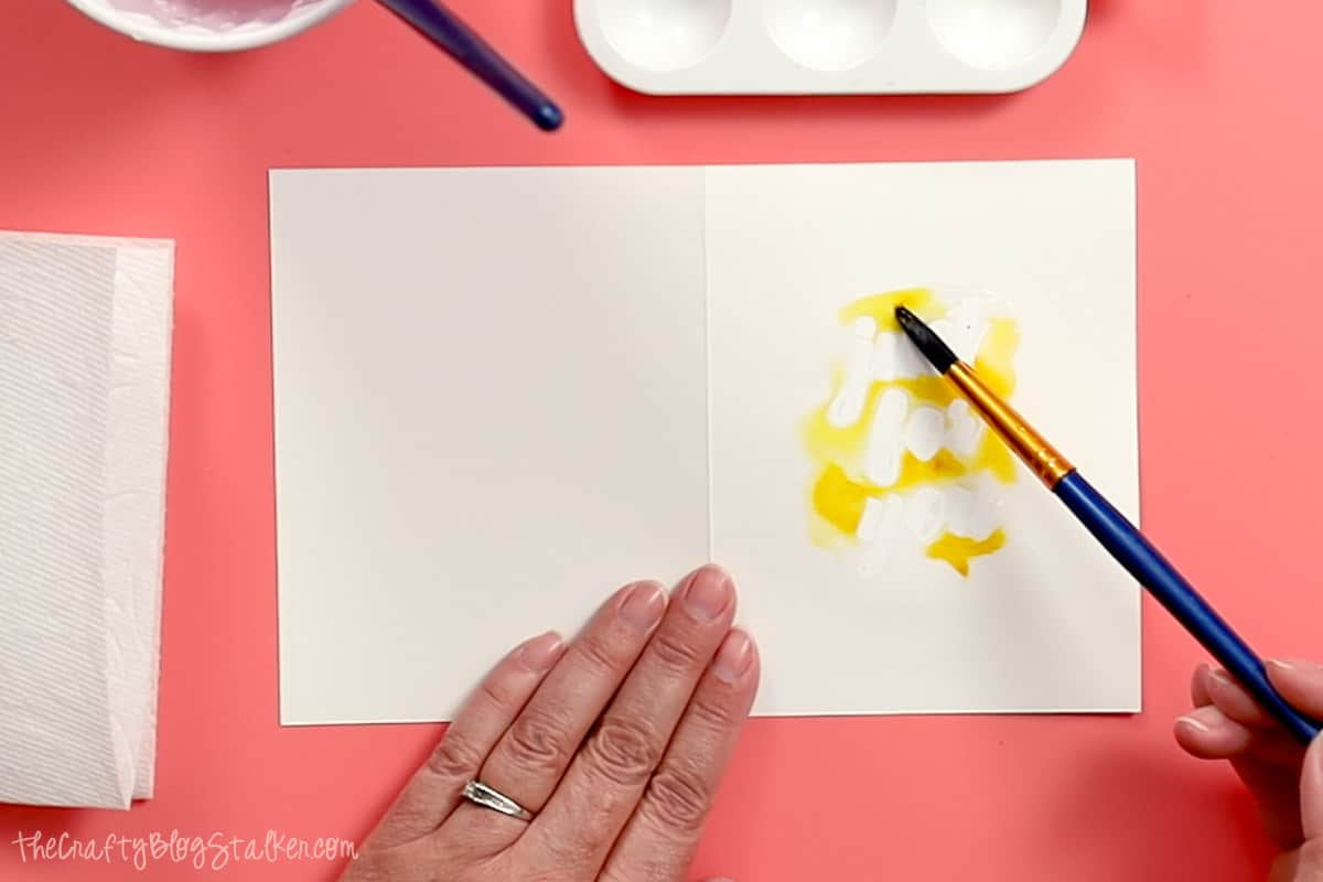 Adding yellow watercolor to a wet wash on a card.