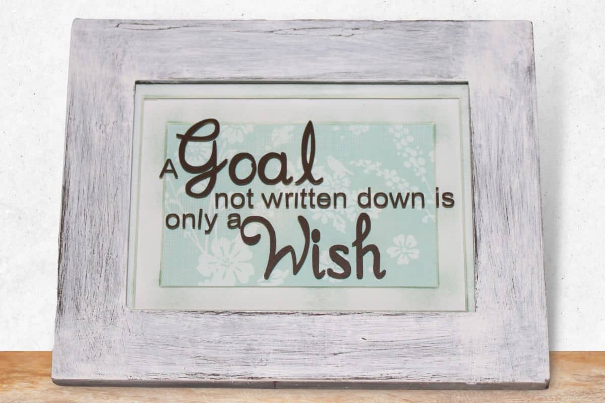 A distressed frame on a shelf with the quote "A goal not written down is only a wish".