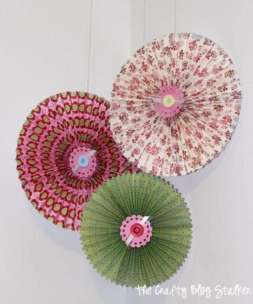 3 paper rosettes of varying sizes hanging on fishing line.