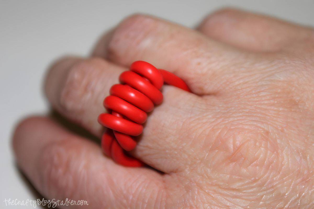 A hand wearing a DIY ring made with electrical wire.