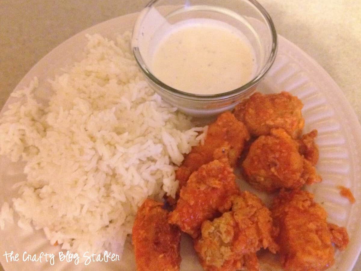 Boneless chicken wings on a plate, with a side of rice, and ranch for dipping.