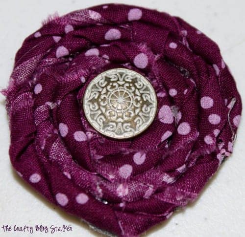 an image of finished fabric rolled flower with a button in the center