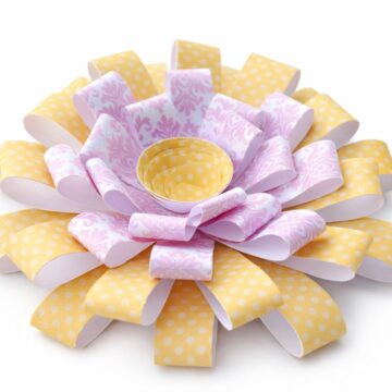 Layered paper flower made from curled strips with polka dot and patterned paper, arranged in a chrysanthemum style with a small center cup