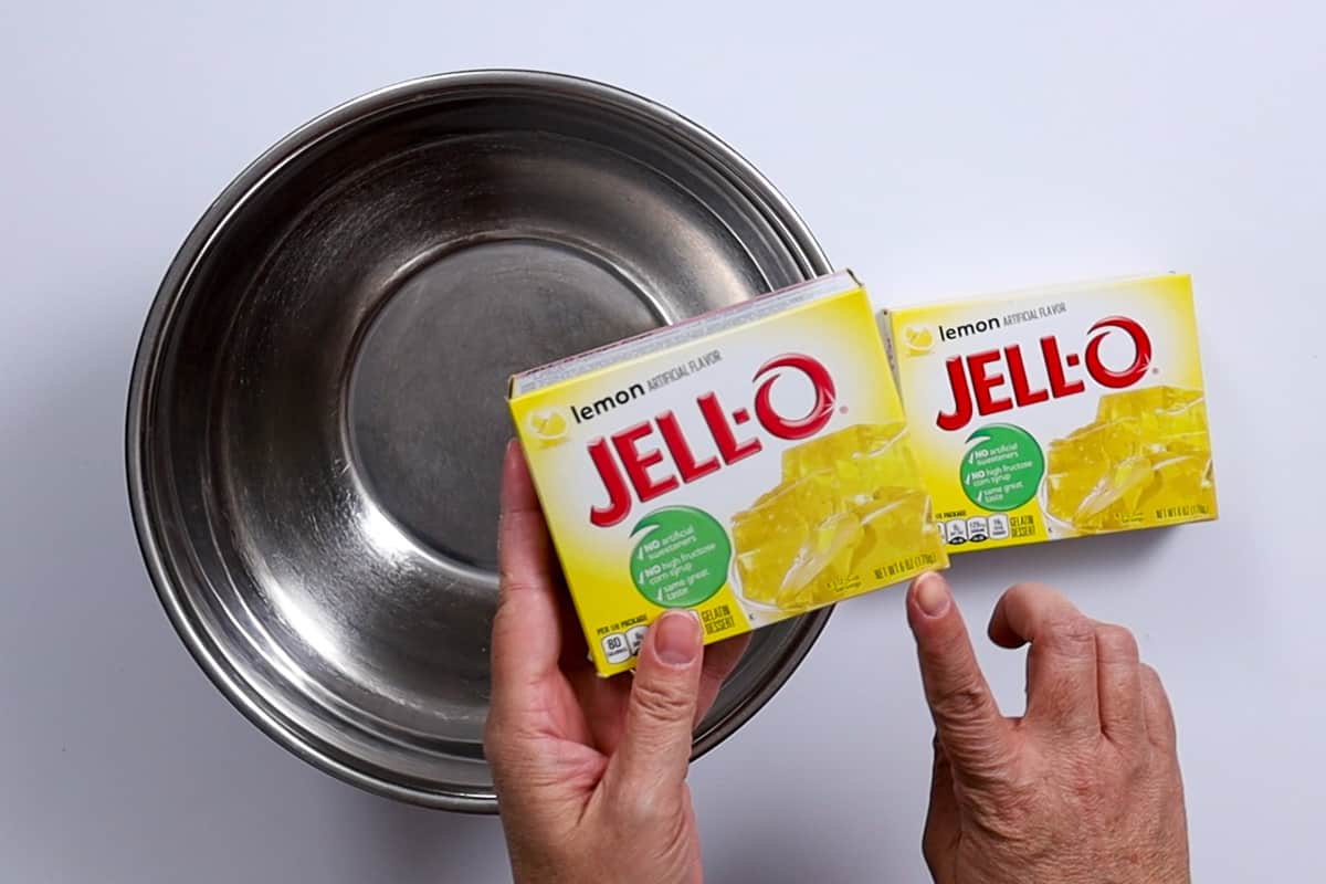 Two boxes of jello mix and a metal mixing bowl.