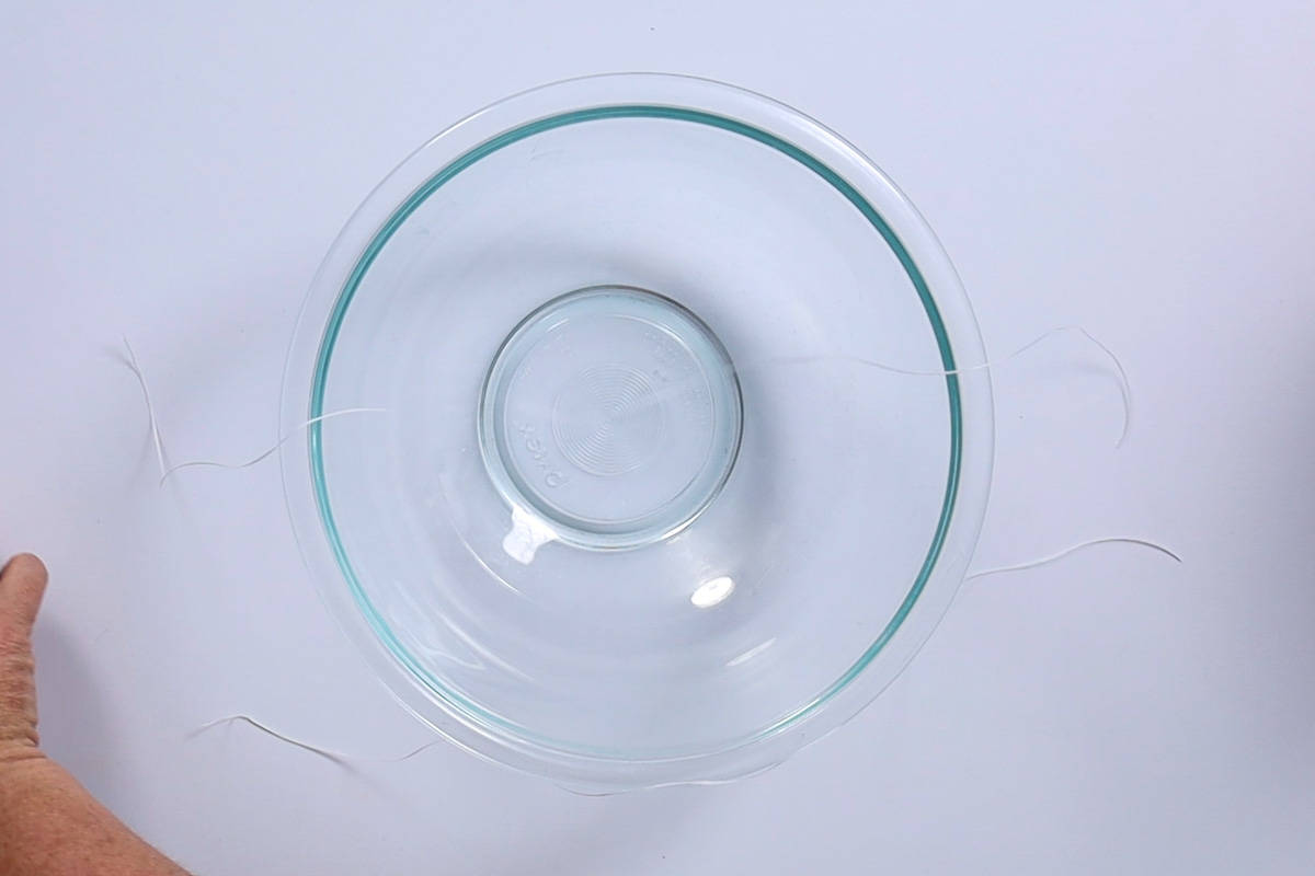 Dental floss draped across a glass mixing bowl.