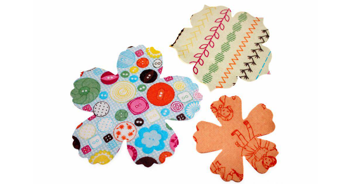 Three fabric flower shapes in playful patterns: one with colorful buttons, another with geometric stitches, and the third featuring vintage doll illustrations.
