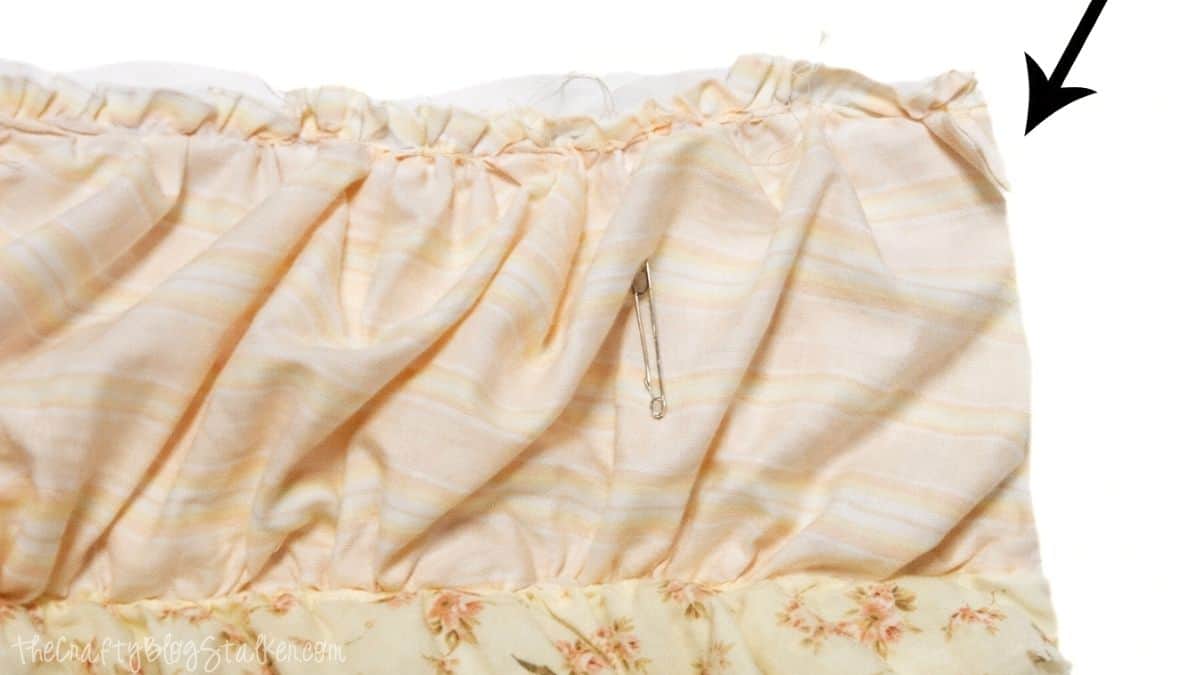 8- trim edges Close-up of ruffled quilt fabric with excess batting and backing extending past the edge, showing where layers will be trimmed before finishing.