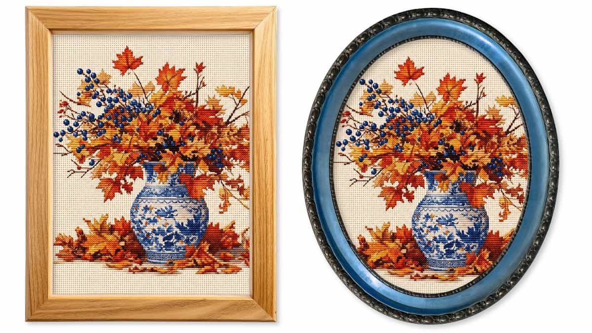 Framed faux cross stitch fall printable featuring a blue floral vase filled with autumn leaves and berries, displayed in both rectangular and oval frames.