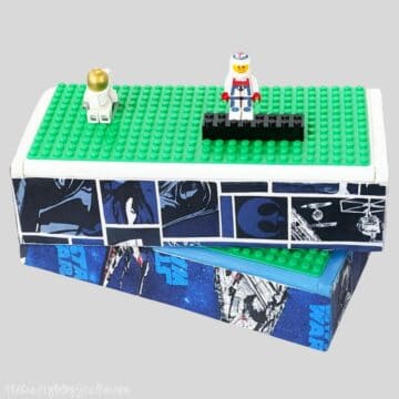 Two LEGO minifigures stand on a green baseplate lid of a Star Wars–themed storage box, designed to hold and play with LEGO pieces while traveling.