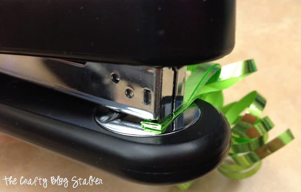 Stapling the folded ends of the curling ribbon together.