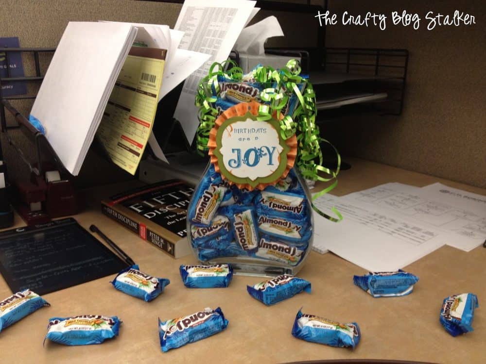 Birthday candy jars placed on a desk with more candy bars laying around it.