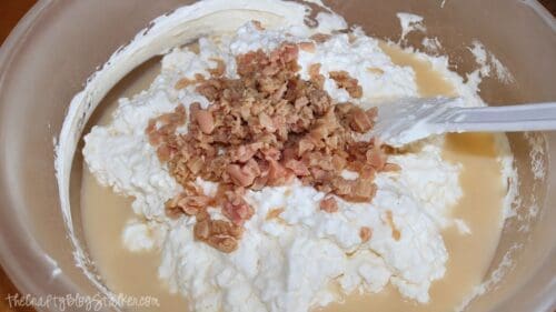 Cottage cheese, softened cream cheese, and minced clams in a mixing bowl with a spatula for making homemade clam dip.