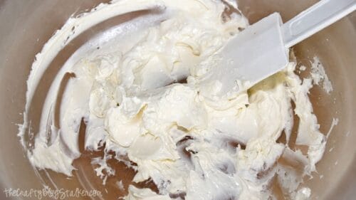 Cream cheese softened in a microwave-safe bowl with a white spatula for making creamy cottage cheese clam dip.