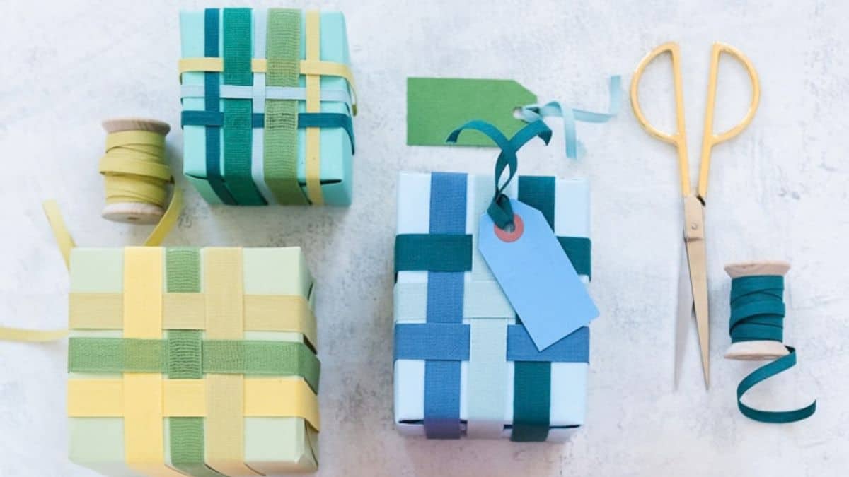 Gift boxes decorated with woven ribbons in blue, green, teal, and yellow, alongside ribbon spools, gift tags, and scissors.
