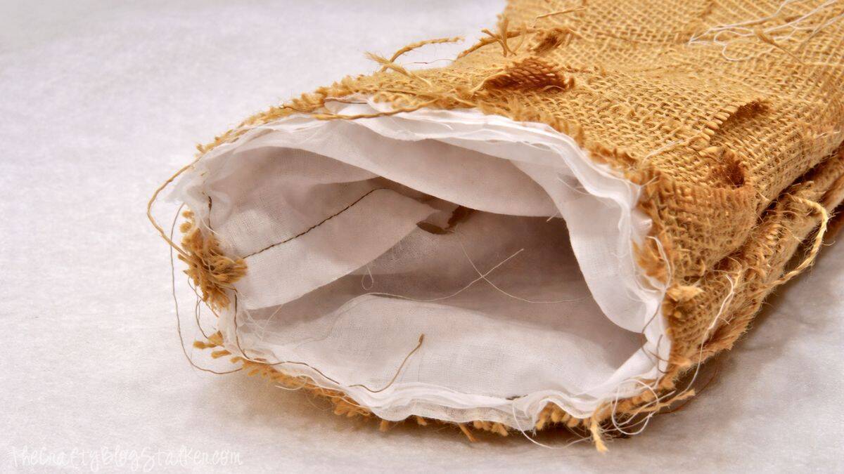 Weaved Burlap Christmas Stockings Tutorial Close-up of a burlap stocking with a white fabric cuff sewn on, showing the inside lining and raw burlap edges during the assembly process.