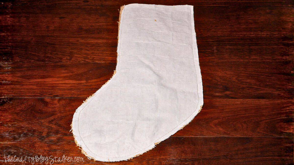 Weaved Burlap Christmas Stockings Tutorial Fabric stocking shape with a sewn lining, showing stitched edges and seams laid flat on a wooden work surface during a DIY stocking project.