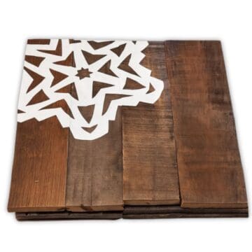 Stack of rustic wooden chargers featuring white paper snowflake designs, creating a handmade winter or holiday table decoration.