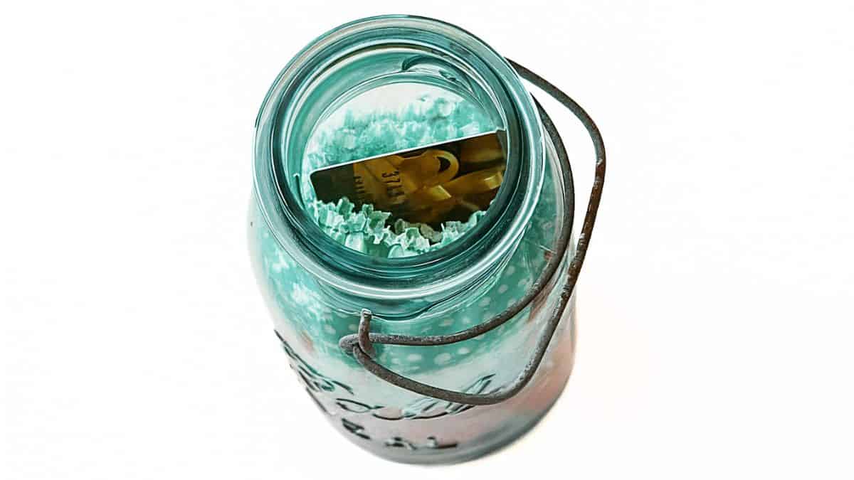 Top view of a vintage blue mason jar filled with shredded paper and a gift card tucked inside.