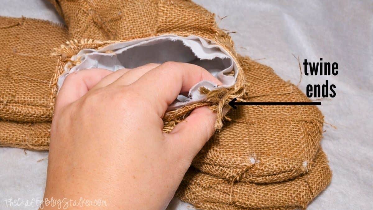 Weaved Burlap Christmas Stockings Tutorial Hand holding the cuff of a burlap stocking, showing twine ends tucked inside the opening during the finishing step of a DIY woven burlap stocking.