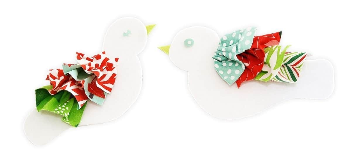 Two handmade white felt bird ornaments with ruffled red, green, and aqua fabric tails and felt beaks, displayed on a white background.