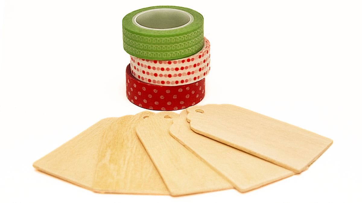 Washi Tape Ornaments made with wooden tags A set of plain wooden gift tags arranged in a fan shape beside three rolls of patterned washi tape for crafting.