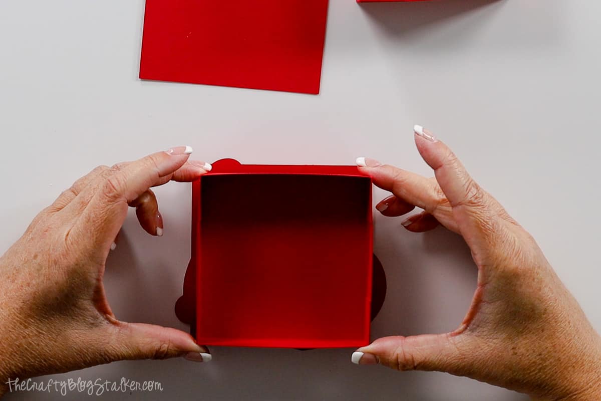 Hands placing the lid box onto the back of the shaped square.