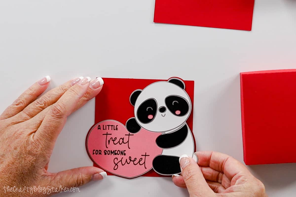 Hands placing the panda and heart on the shaped square.