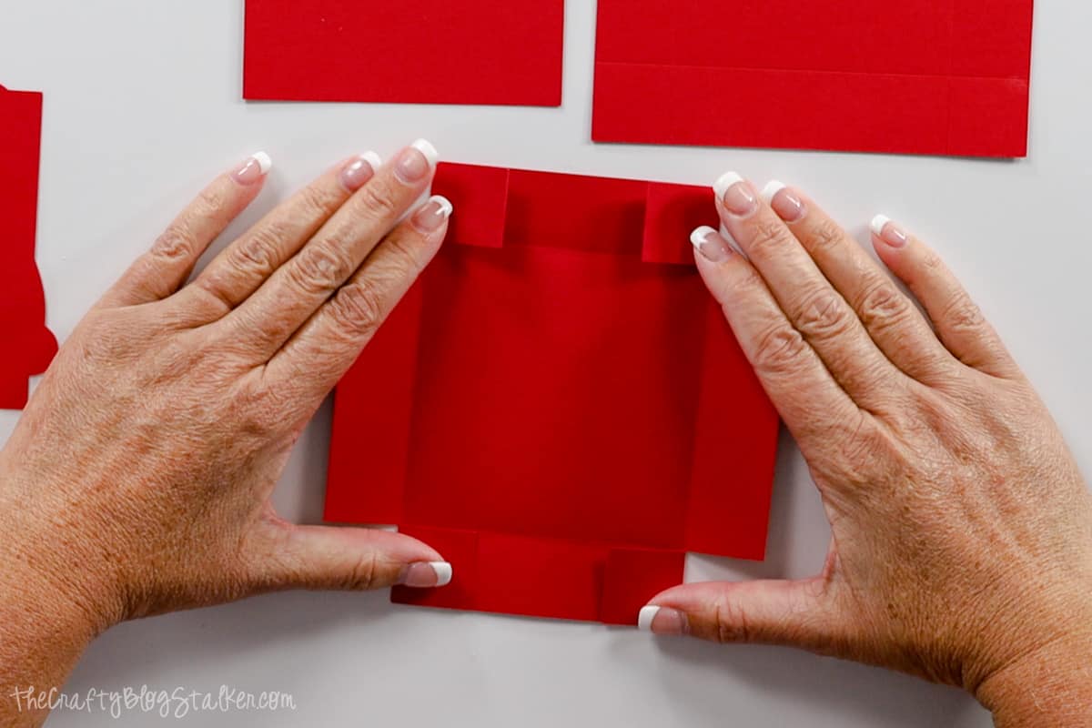 Hands holding the tabs of the square piece.