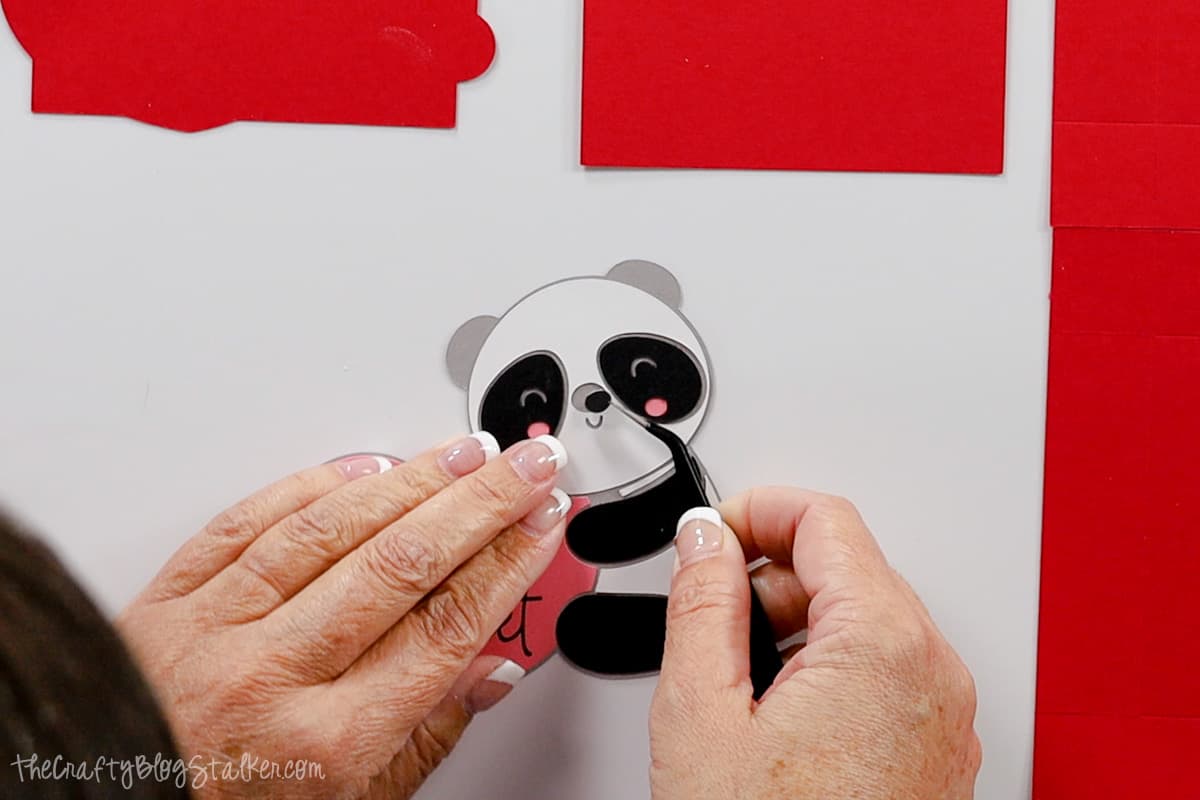Hands using tweezers to put place the nose on the panda.
