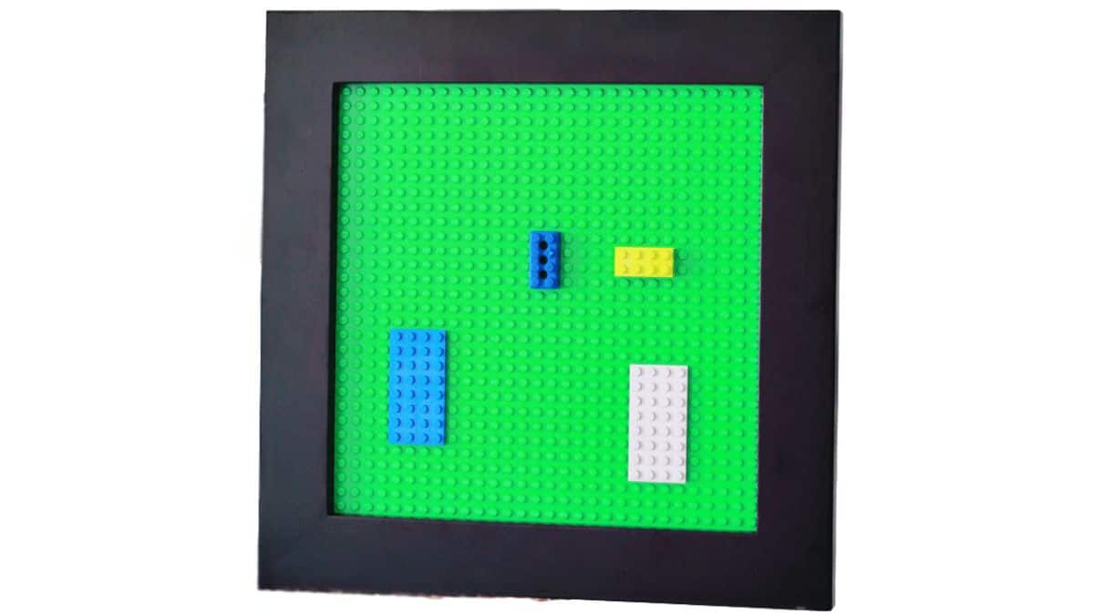 Framed LEGO building tray with a base plate and a few LEGO bricks arranged inside, designed as a simple play and display surface.