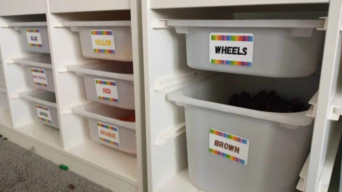 IKEA storage unit with pull-out plastic bins used to organize LEGO bricks, sorted by color groups and parts like wheels for easy building access.