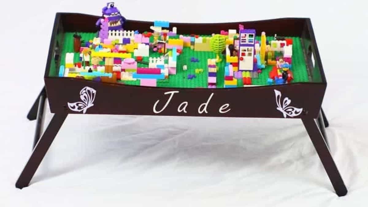 6 Lego Storage Ideas Personalized LEGO play tray table filled with colorful LEGO bricks and builds, featuring a raised edge and the name Jade on the front.