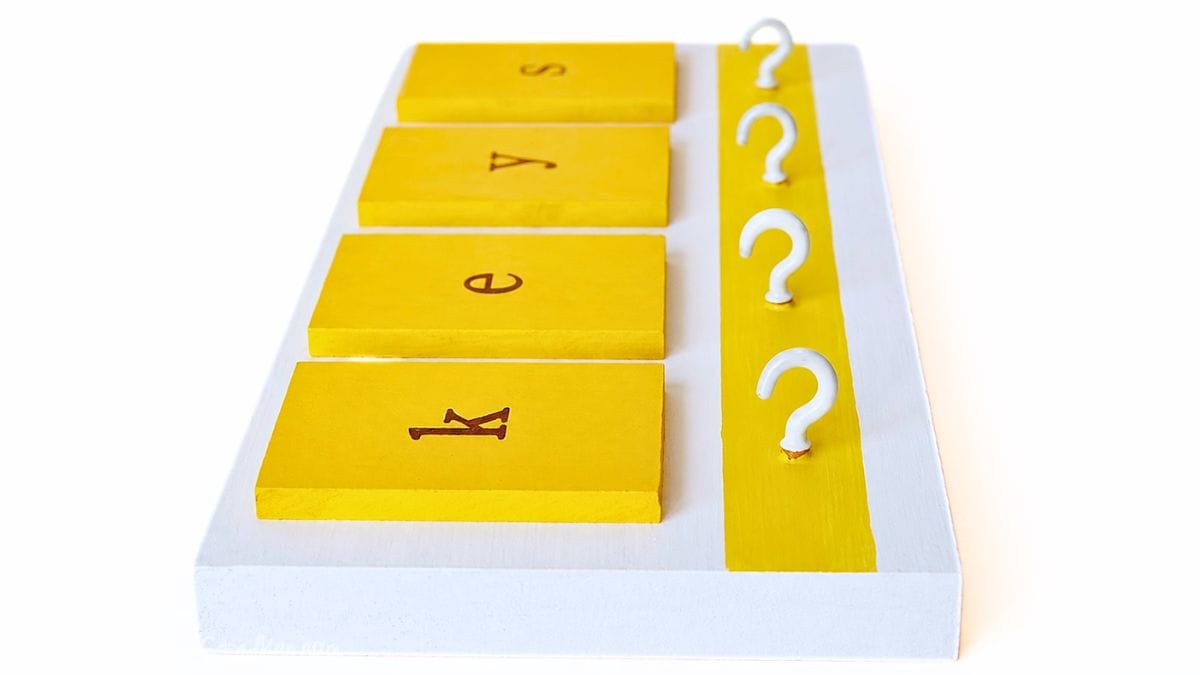 Side view of a yellow and white DIY key holder with tiles spelling 