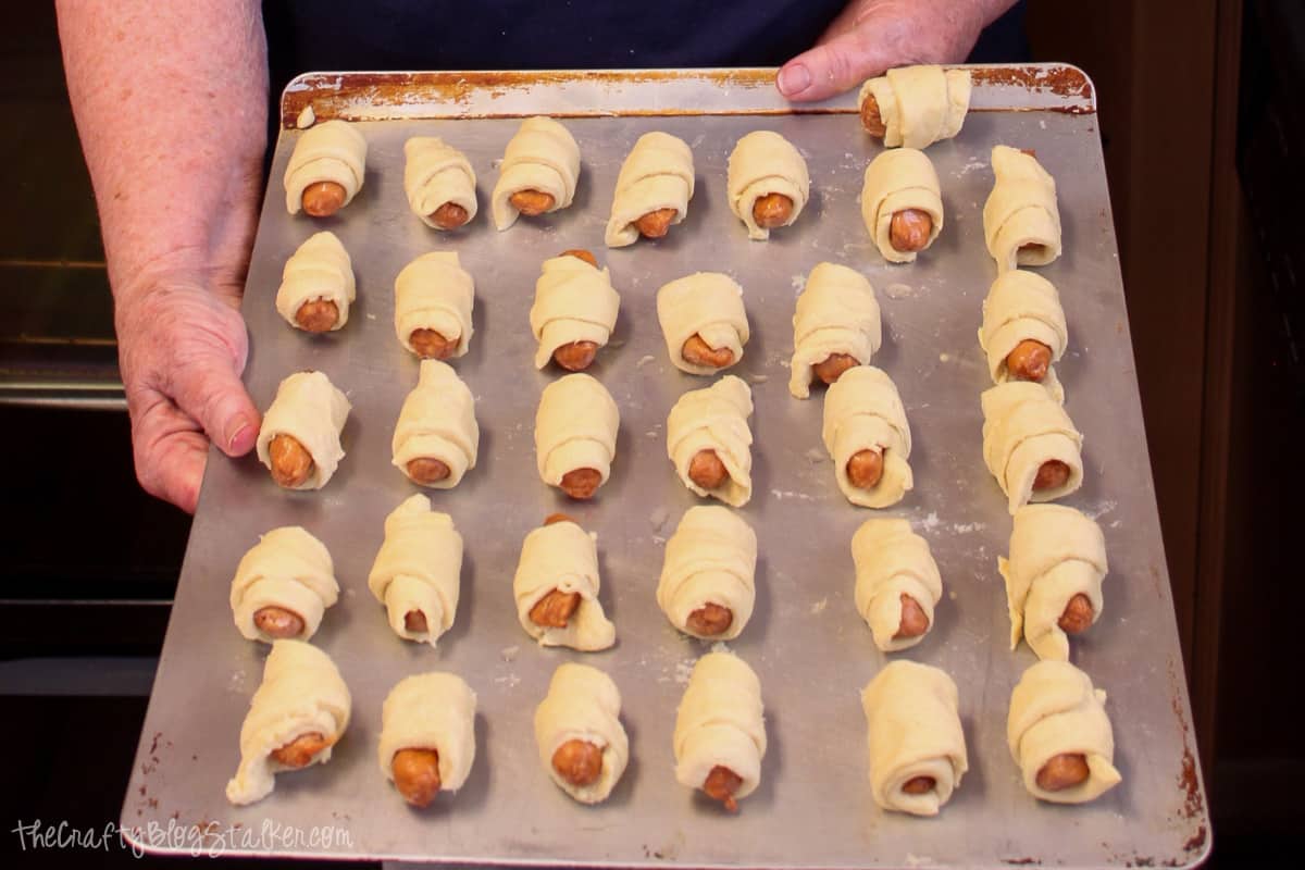 Pigs in a blanket on a baking sheet before putting them in the oven.