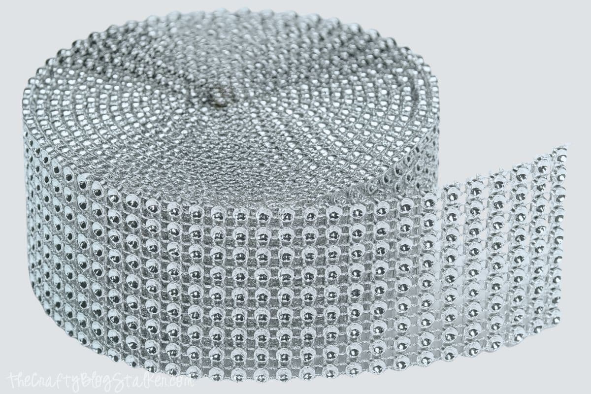 A roll of silver rhinestone mesh ribbon, often called "bling on a roll," used for decorating crafts, clothing, or accessories with a sparkling effect.