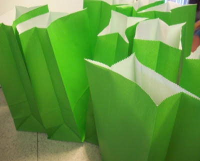 many green paper sacks that are open on a table