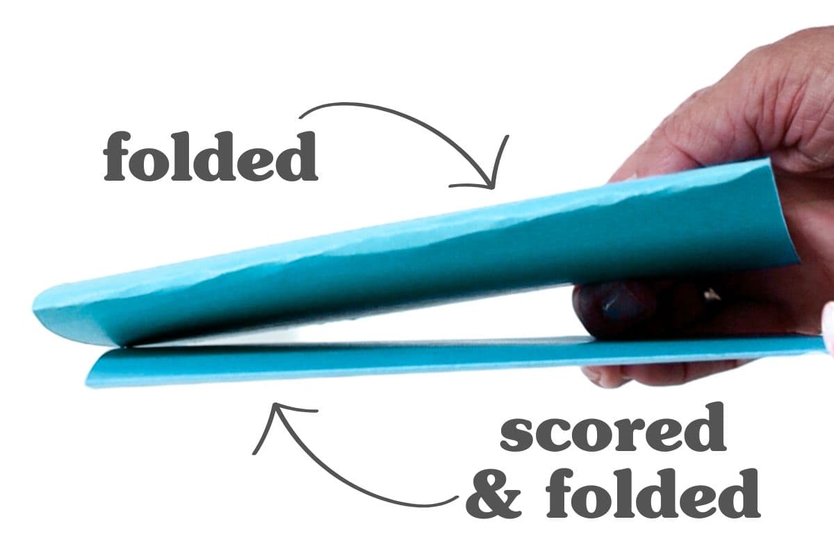 Side-by-side comparison of two folded teal paper pieces, one simply folded and one scored then folded, highlighting the cleaner fold from scoring.