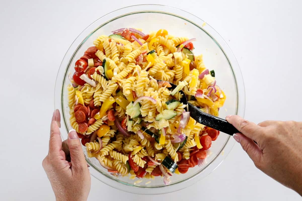 Stirring all of the ingredients to the pasta salad together.